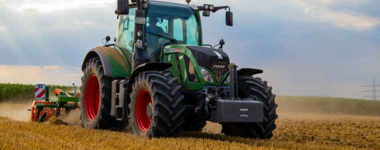 green tractor plowing the fields on focus photography
